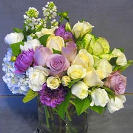 Mixed bouquet of roses, calla lilies, and hydrangeas in a glass vase