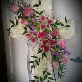 Cross-shaped floral spray with white blooms, pink roses, and lilies