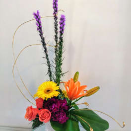 Mixed bouquet with orange lilies, yellow gerbera, and pink roses in a white vase