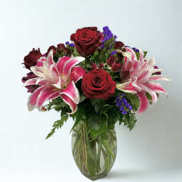Bouquet of red roses and pink lilies in a clear glass vase
