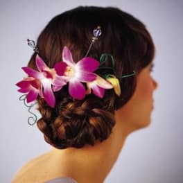 Woman wearing a purple orchid hairpiece in an updo