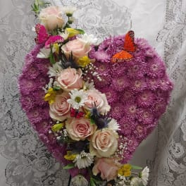 Heart-shaped floral arrangement with pink roses and purple blooms