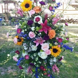 Tall standing floral spray with sunflowers, lilies, and mixed blooms