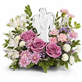 Pink roses and white lilies arranged around a clear angel figurine