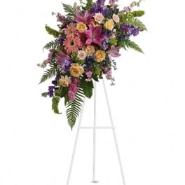 Standing floral spray with pink, purple, and peach flowers on a white easel