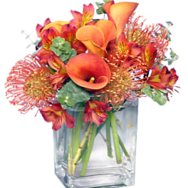 Orange and red floral arrangement in a clear glass vase
