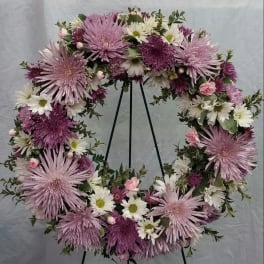 Lavender and white floral wreath on a black stand