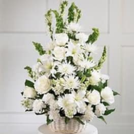 White floral arrangement in a wicker basket with tall green accents