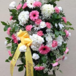 Standing floral spray of pink and white flowers with a yellow ribbon
