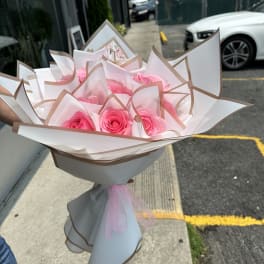 Bouquet of pink roses wrapped in white and tan paper