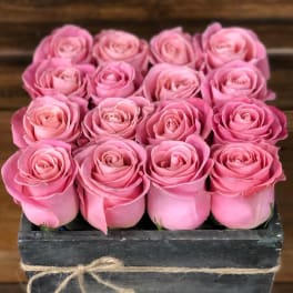 Pink roses arranged in a rustic wooden box tied with twine