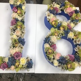 Floral arrangement shaped like the number 18 with roses and orchids