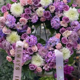 Heart-shaped floral wreath with pink and purple blooms and satin ribbons