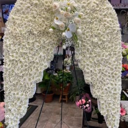 Large white floral funeral spray on a stand with orchids and roses