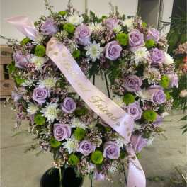 Heart-shaped floral wreath with lavender roses and white blooms on a stand