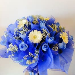 Blue bouquet with white daisies and small filler flowers in a vase