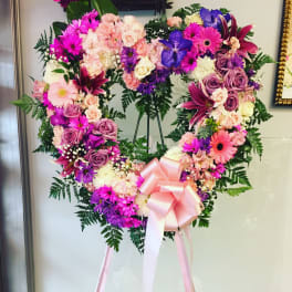 Heart-shaped floral wreath with pink, purple, and white flowers on an easel