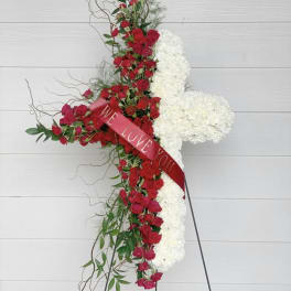 Standing floral cross with red roses and white flowers on an easel