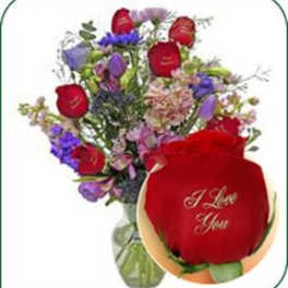 Mixed bouquet with red roses and purple flowers in a glass vase