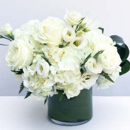 White roses and hydrangeas arranged in a dark green vase