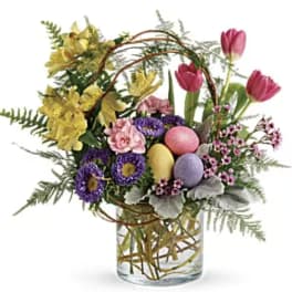 Colorful spring bouquet in a clear glass vase with decorative eggs