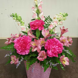 Pink and white floral arrangement in a glittery pink container