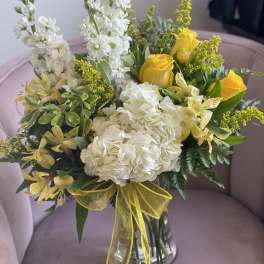 Bouquet of white and yellow flowers in a clear glass vase