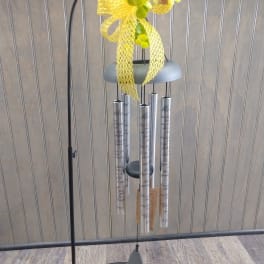 Yellow ribbon-topped wind chime with silver tubes on a black stand