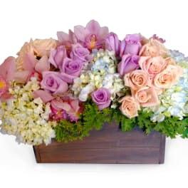 Pastel bouquet of roses, orchids, and hydrangeas in a wooden box
