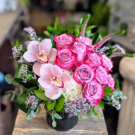 Pink roses and pale orchids arranged in a black vase