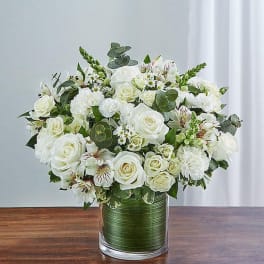 White rose bouquet in a glass vase with mixed greenery