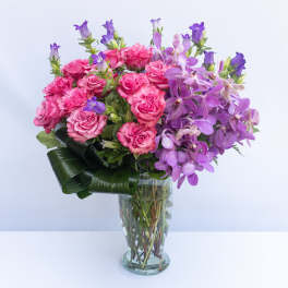 Pink roses and purple orchids in a clear glass vase