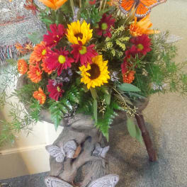 Autumn floral arrangement in a tree-trunk planter with butterfly accents