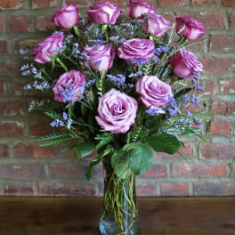 Bouquet of lavender roses with purple filler in a glass vase
