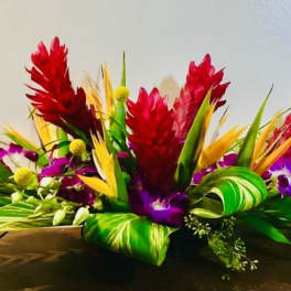 Tropical flower arrangement with red, purple, and yellow blooms in a low container