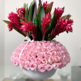 Pink roses in a white bowl with red tropical flowers above