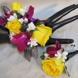 Yellow and magenta floral corsage and boutonniere on black display hands