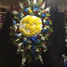 Large standing floral wreath with a yellow and white center and red, blue, and white flowers