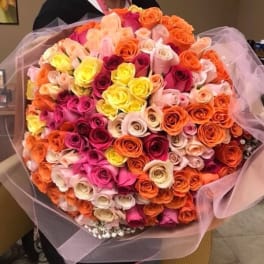 Large bouquet of multicolored roses wrapped in pink tulle