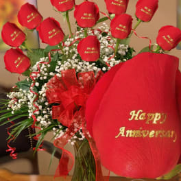 Red roses with baby’s breath in a glass vase and red ribbon