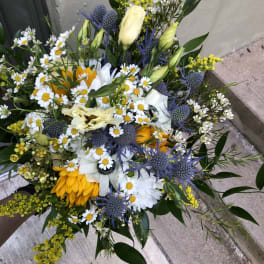 Mixed bouquet with white daisies, yellow blooms, and blue thistle-like flowers