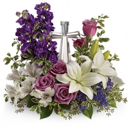 Purple and white floral arrangement with a silver cross centerpiece
