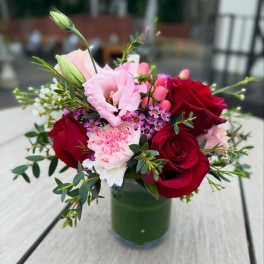 Bouquet of red roses and pink blooms in a glass vase