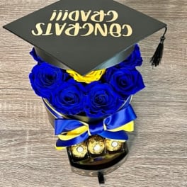 Blue roses arranged under a graduation cap with chocolates and ribbon