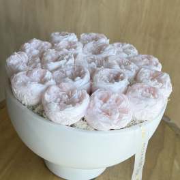Round box of pale pink peonies with a ribbon tag