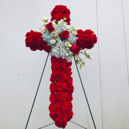 Red floral cross on a stand with white and blue flowers