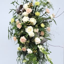 Tall floral standing spray with white and peach blooms on a metal easel
