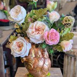 Arrangement of pale pink and white roses in a copper heart vase