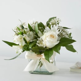 White rose and lily bouquet in a glass vase with a ribbon