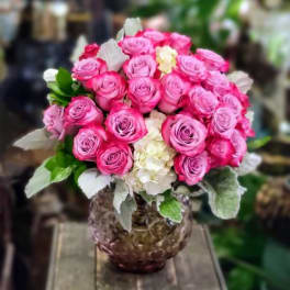 Pink rose bouquet in a glass vase with white hydrangea accents
